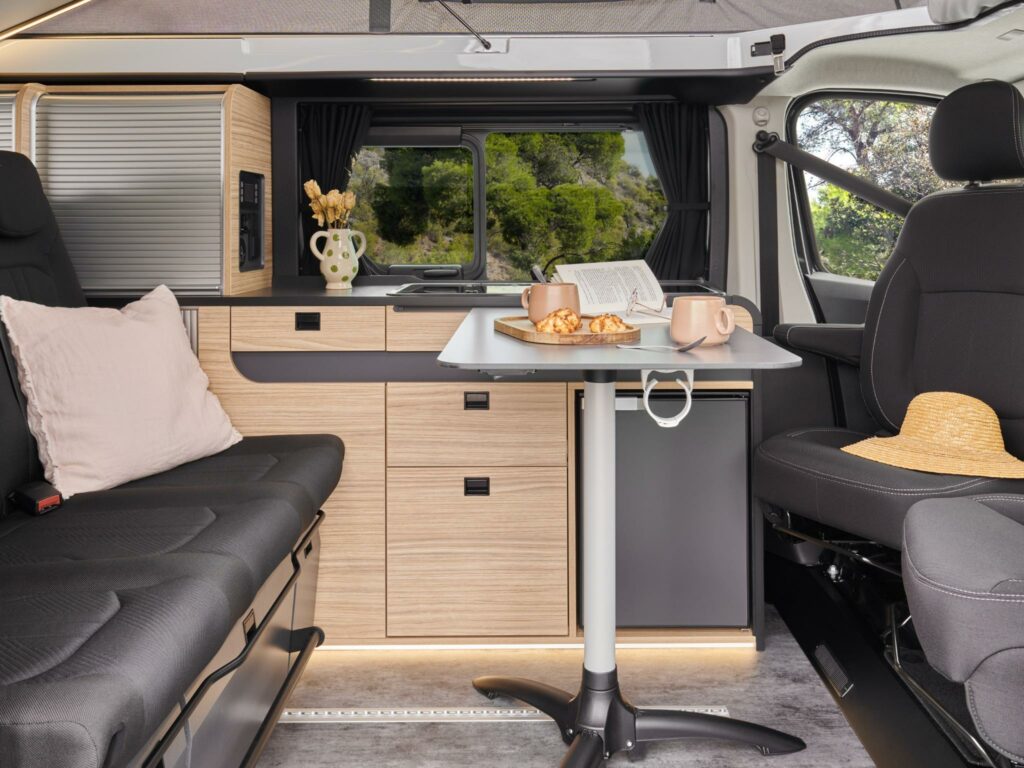 Photo intérieur d'un van aménagé Bavaria MC545BC avec le toit relevé et la table installée