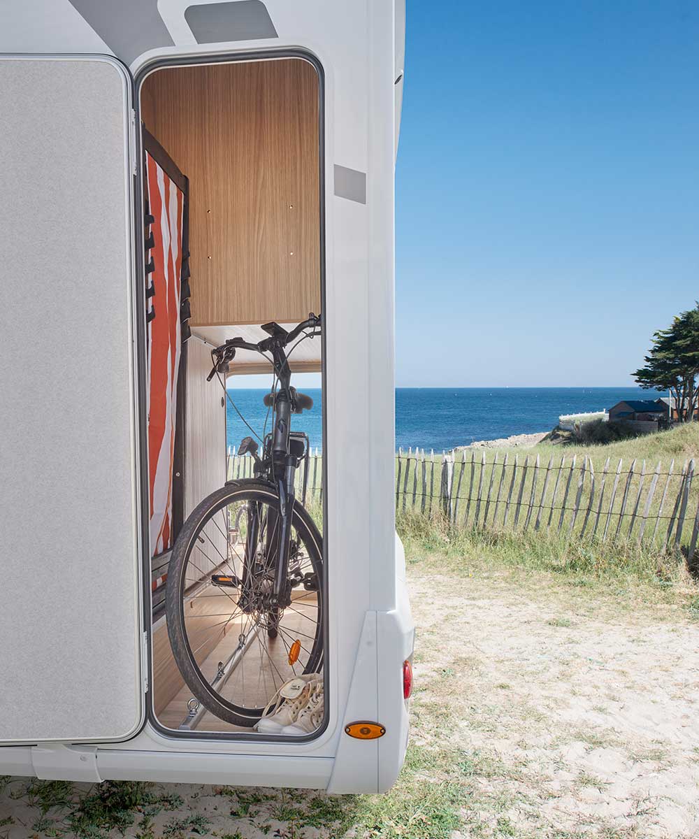 Soute du camping-car profilé T690D Bavaria dans un décor de bord de mer.