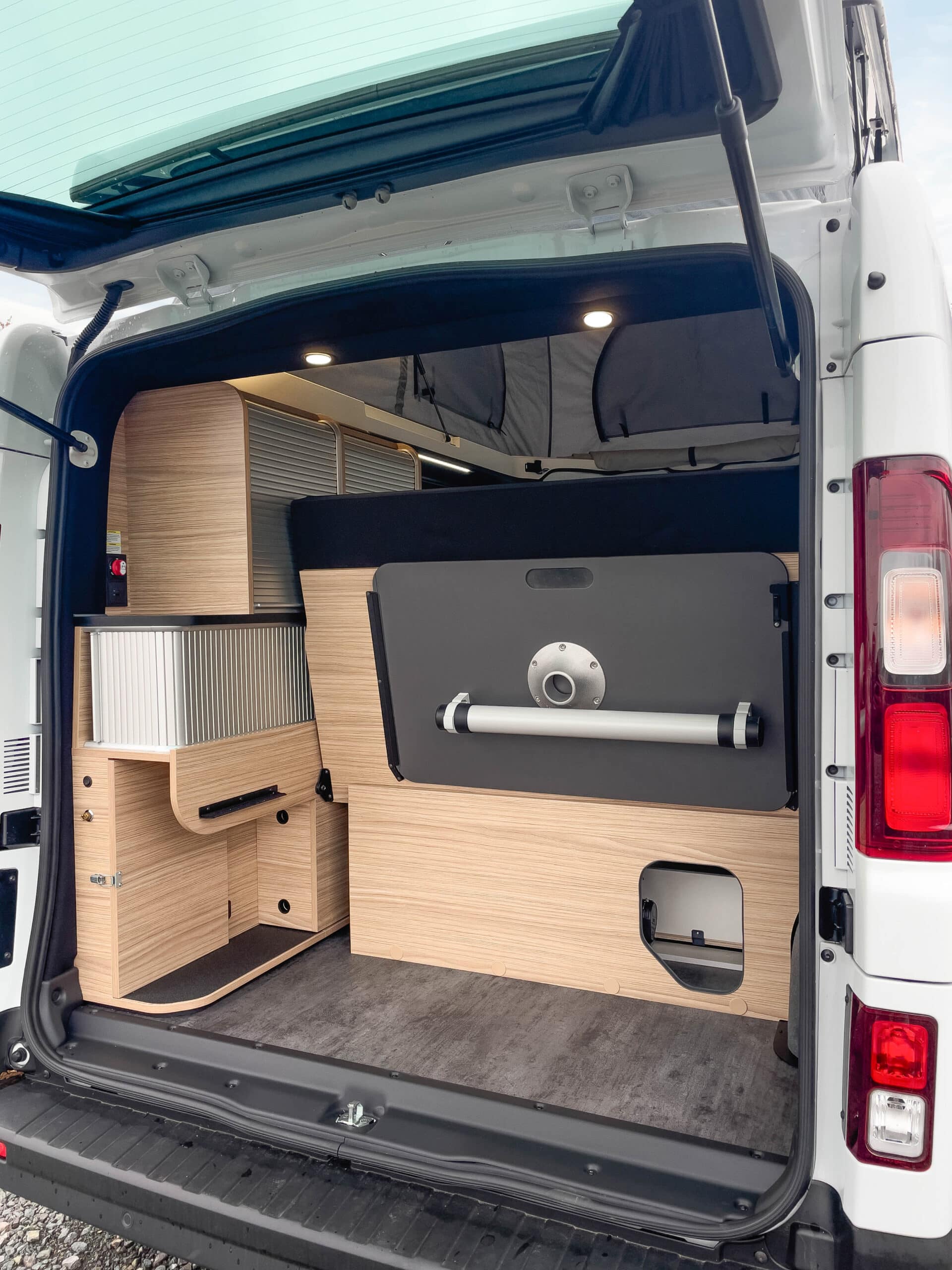 Photo de l'arrière d'un van aménagé Bavaria MC504BF avec le coffre ouvert et la banquette repliée