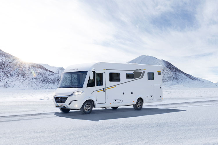 Camping-car intégral Bavaria roulant sur une route enneigée