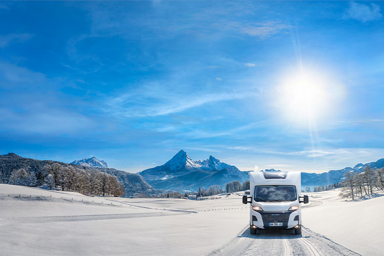 Camping-car profilé Bavaria roulant sur une route enneigée
