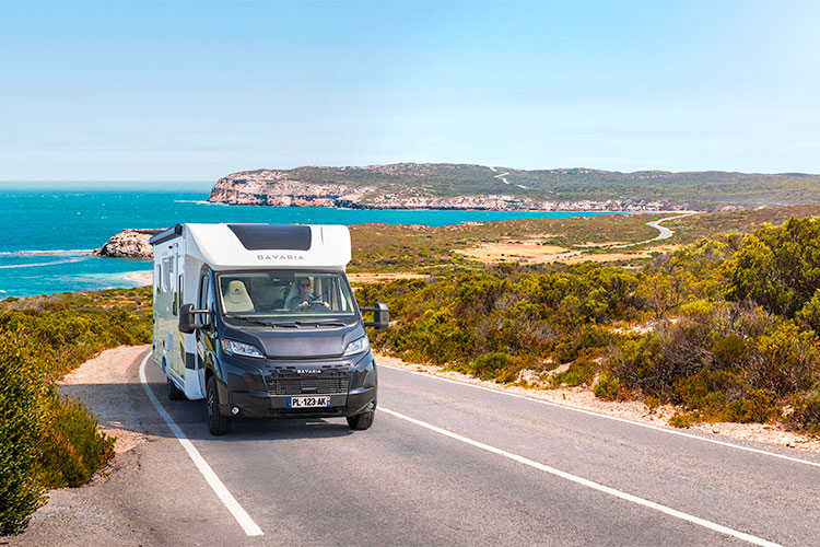 Camping-car profilé Bavaria roulant sur une route en bord de mer