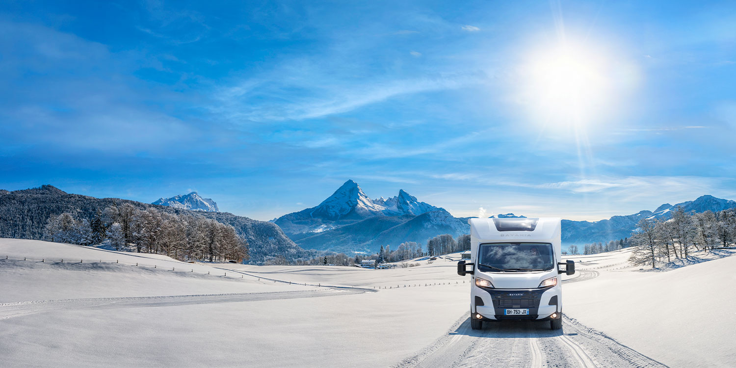 Camping-car profilé Bavaria roulant sur une route enneigée
