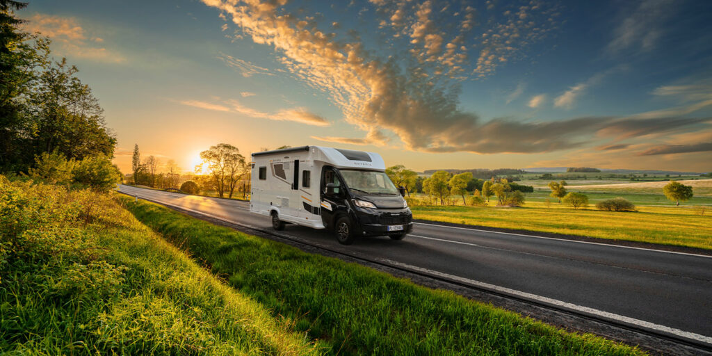 Camping-car profilé Bavaria roulant sur une route en campagne