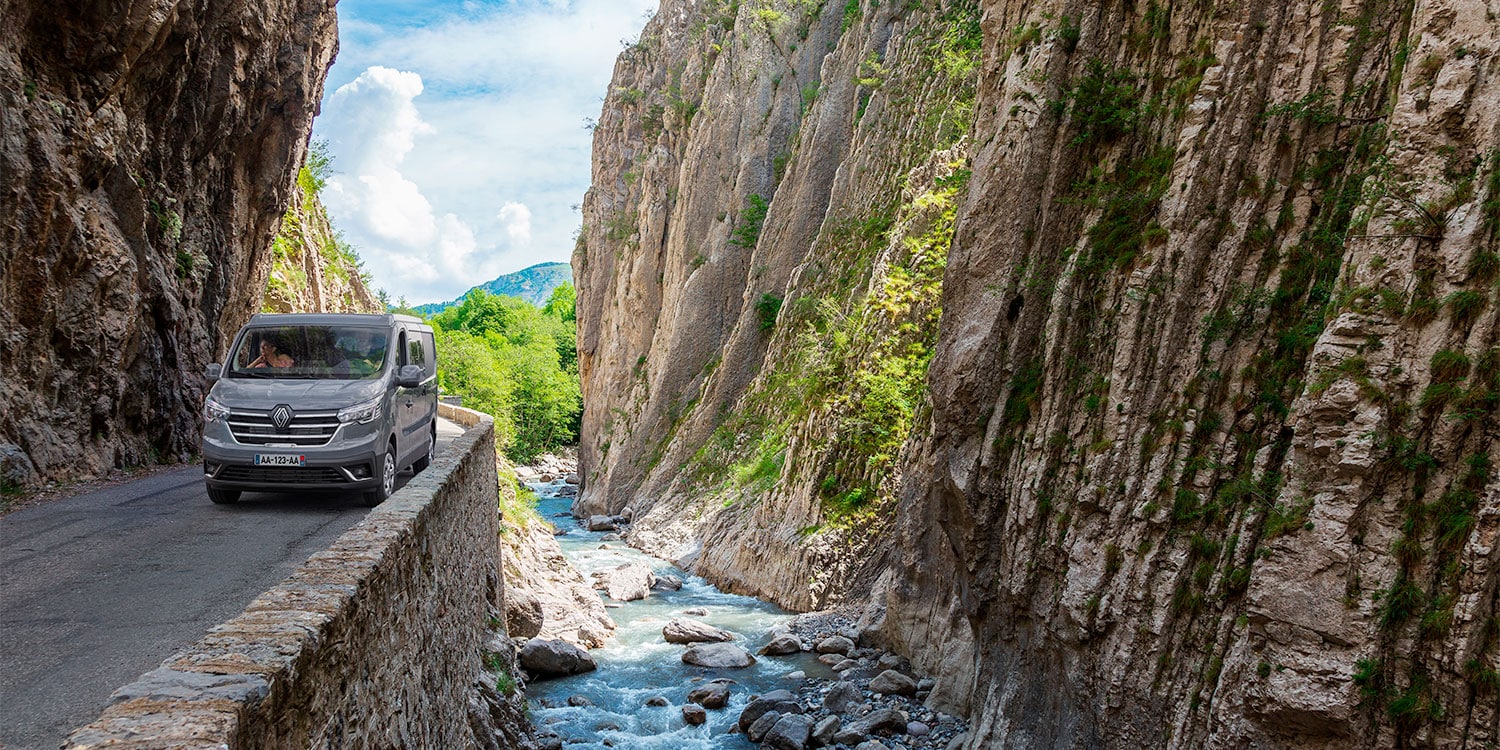 Van aménagé Bavaria sur une route étroite le long d'une rivière