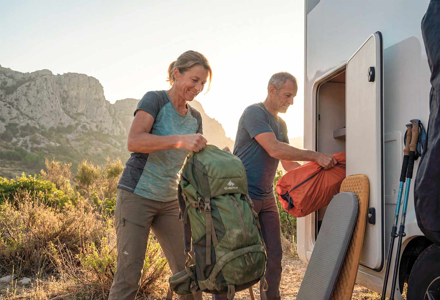 Couple se préparant à partir en randonné, prenant leur sac dans la soute de leur camping car