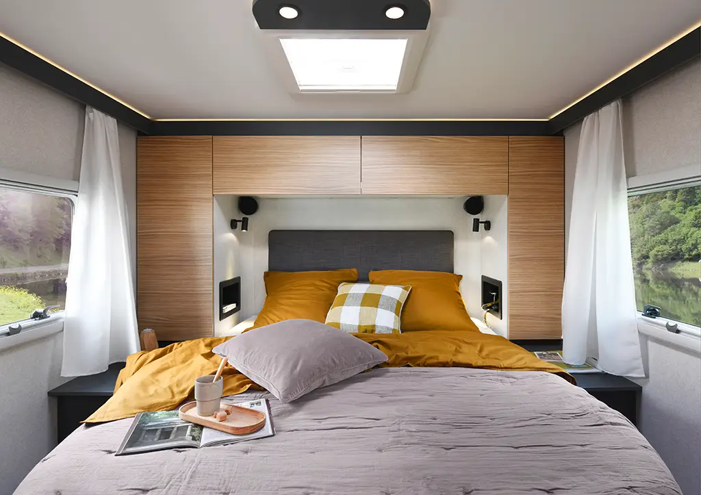 Chambre d'un camping car intégral avec grand lit et placards hauts
