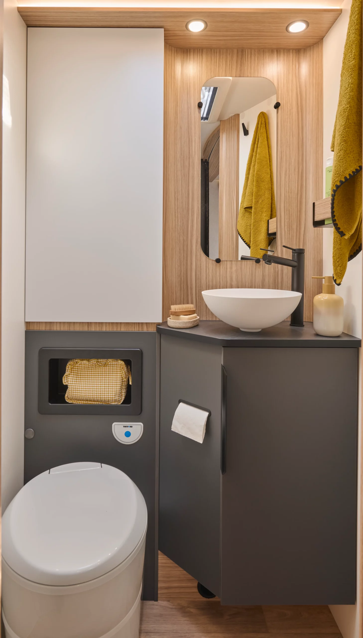 Salle de bain d'un camping car intégral avec toilettes, salle de bain et miroirs