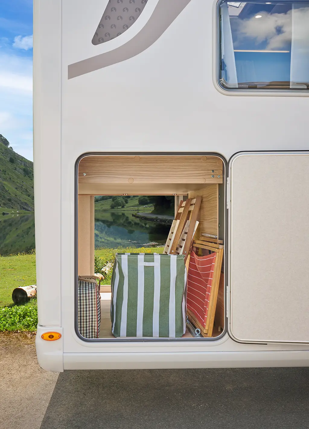 Soute traversante d'un camping car intégral avec rangements en bois clairs