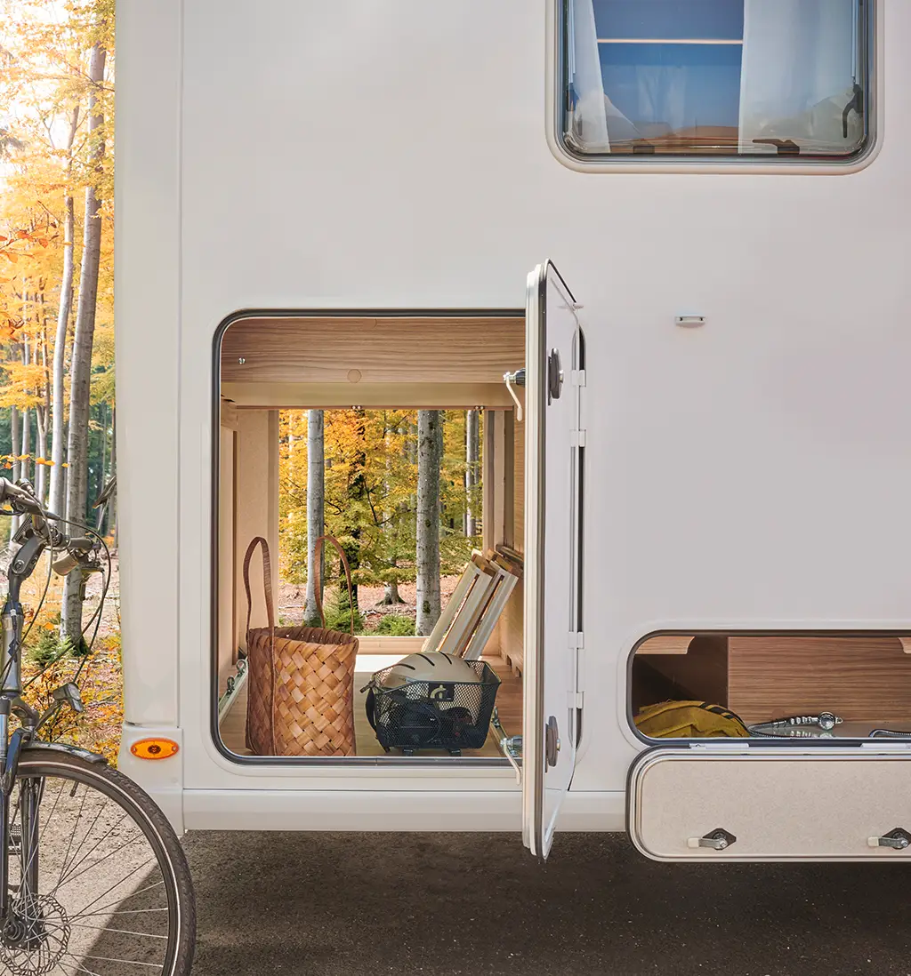 Soute traversante d'un camping car intégral avec rangements en bois clair