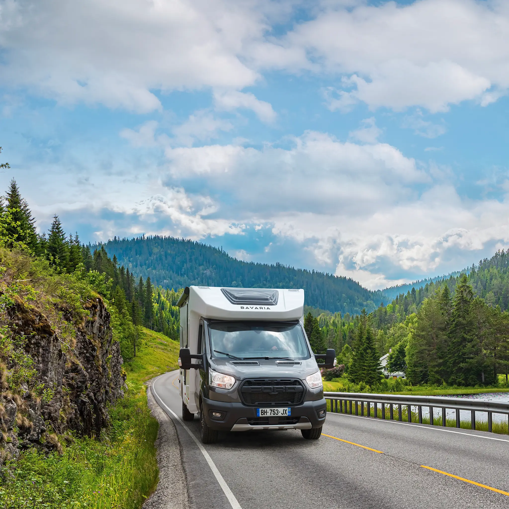 Camping car profilé étroit sur une route au bord d'une rivière