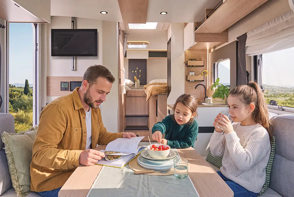 Intérieur d'un camping car profilé étroit avec banquette, table en bois et rangements
