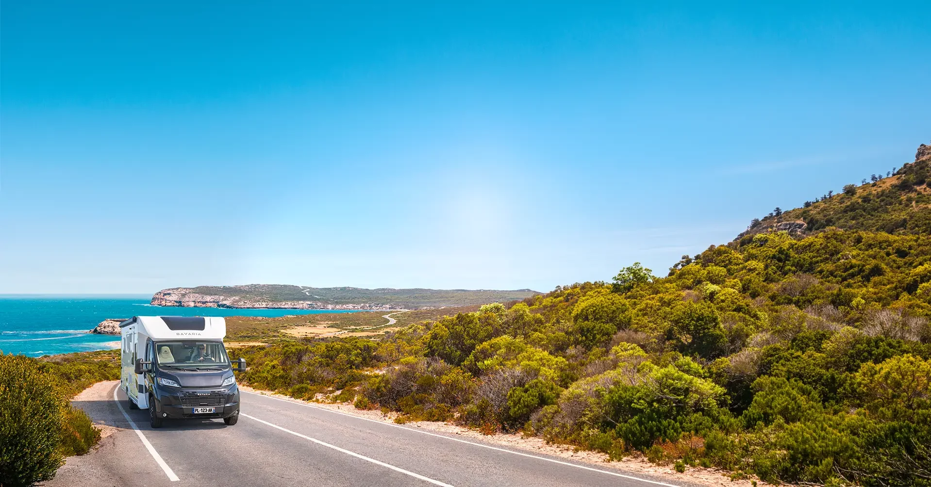 Camping car profilé sur une route au bord de mer