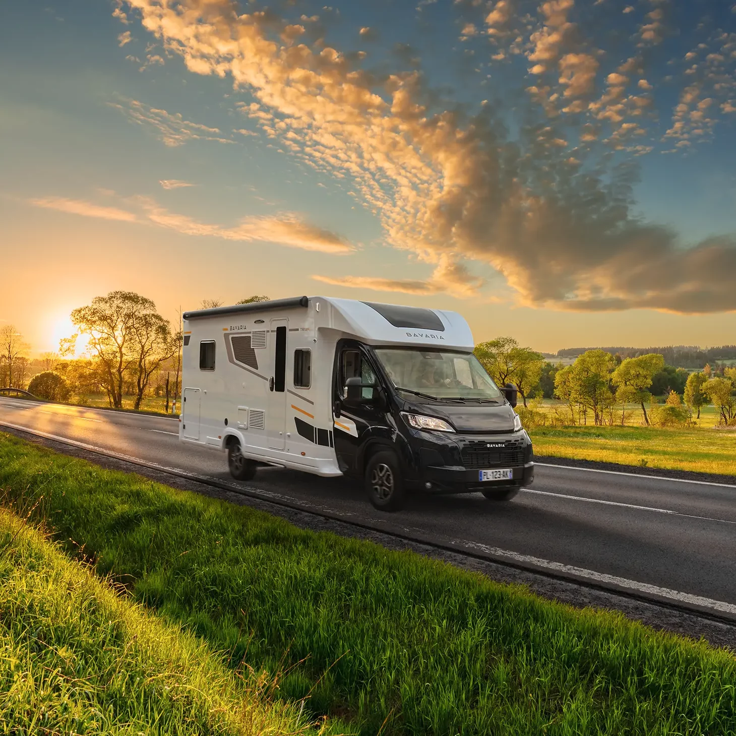 Camping car profilé sur une route de campagne au coucher du soleil